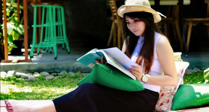 fair skinned Asian woman reading on the lawn.jpg.optimal