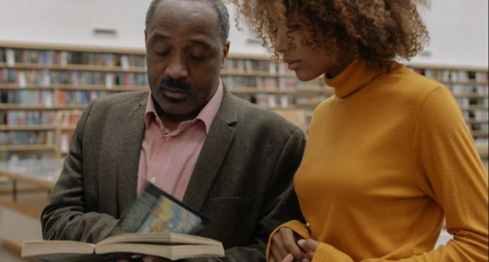 two Black people reading a book in a library 1.jpg.optimal