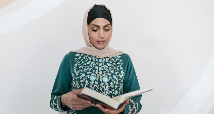 a light brown skinned woman in a Hijab reading a book.jpg.optimal