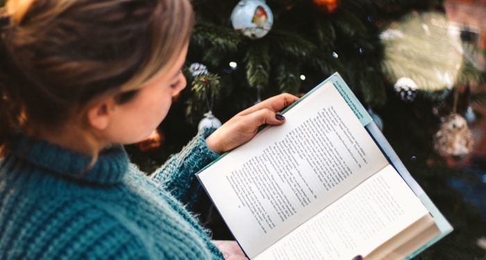 woman reading by the christmas tree for holiday feature 700x375 1.jpg.optimal